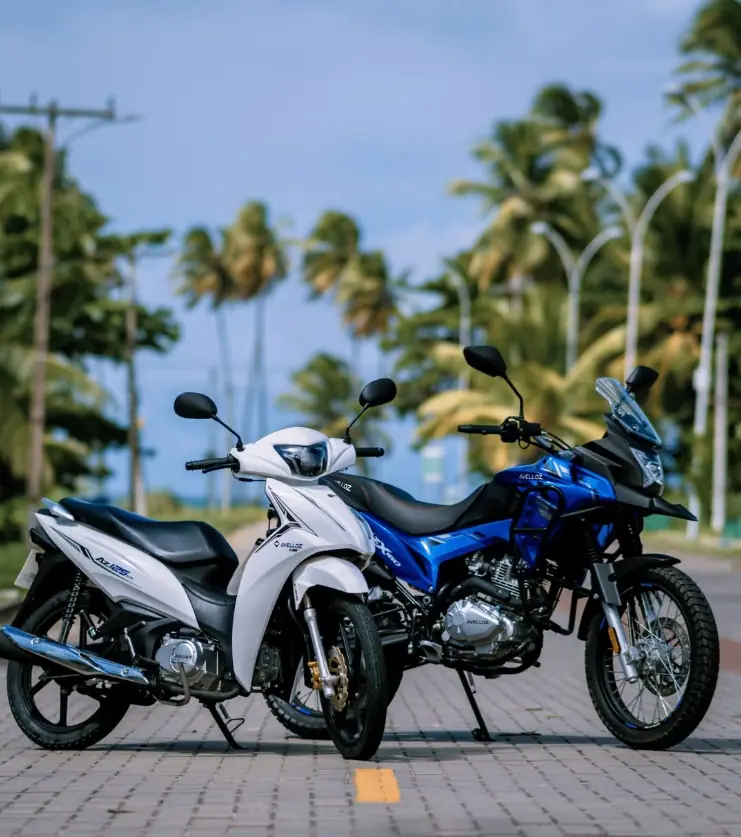 Avelloz AZ125 branca e AZ160 Xtreme azul lado a lado numa avenida com palmeiras em Maracanaú, Ceará
